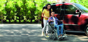 Junge Frau mit Junge im Rollstuhl in der Nähe von Transporter im Freien 