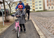 befestigter Fahrradweg in der Rudolf-Breitscheid-Straße neben Kopfsteinpflasterstraße mit 3 Radfahrer hintereinander, Kleinkind mit rosa Puky-Fahrrad und Helm im Vordergrund 